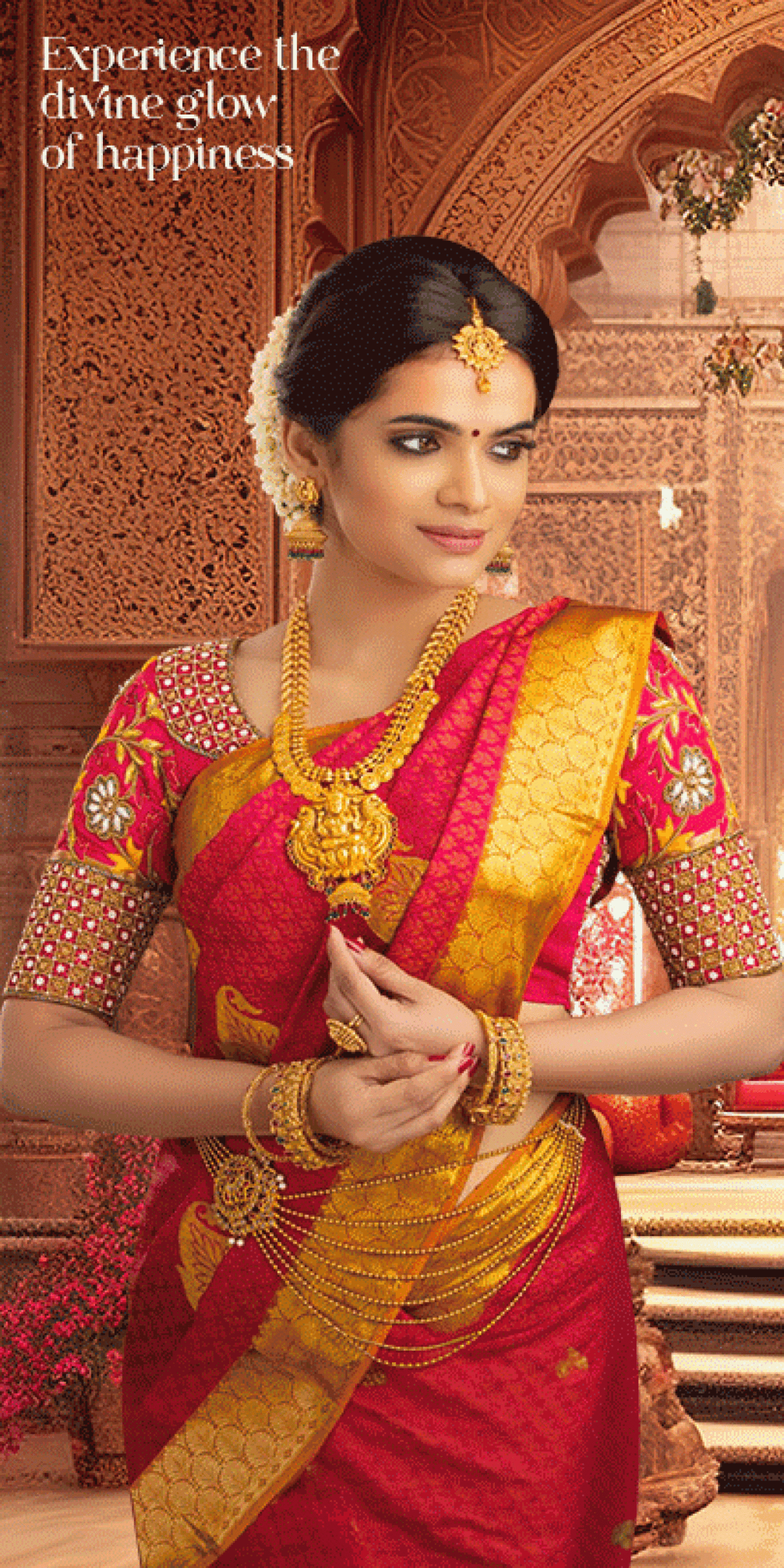 A lady standing in red and gold saree for showing her jewellary